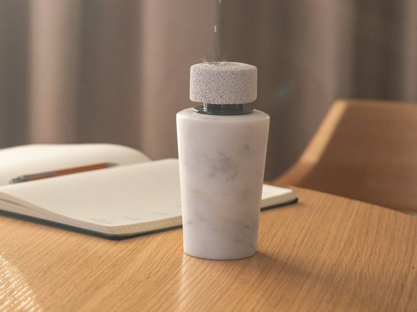 Oil dropping from a small bottle onto the stone of a white marble diffuser