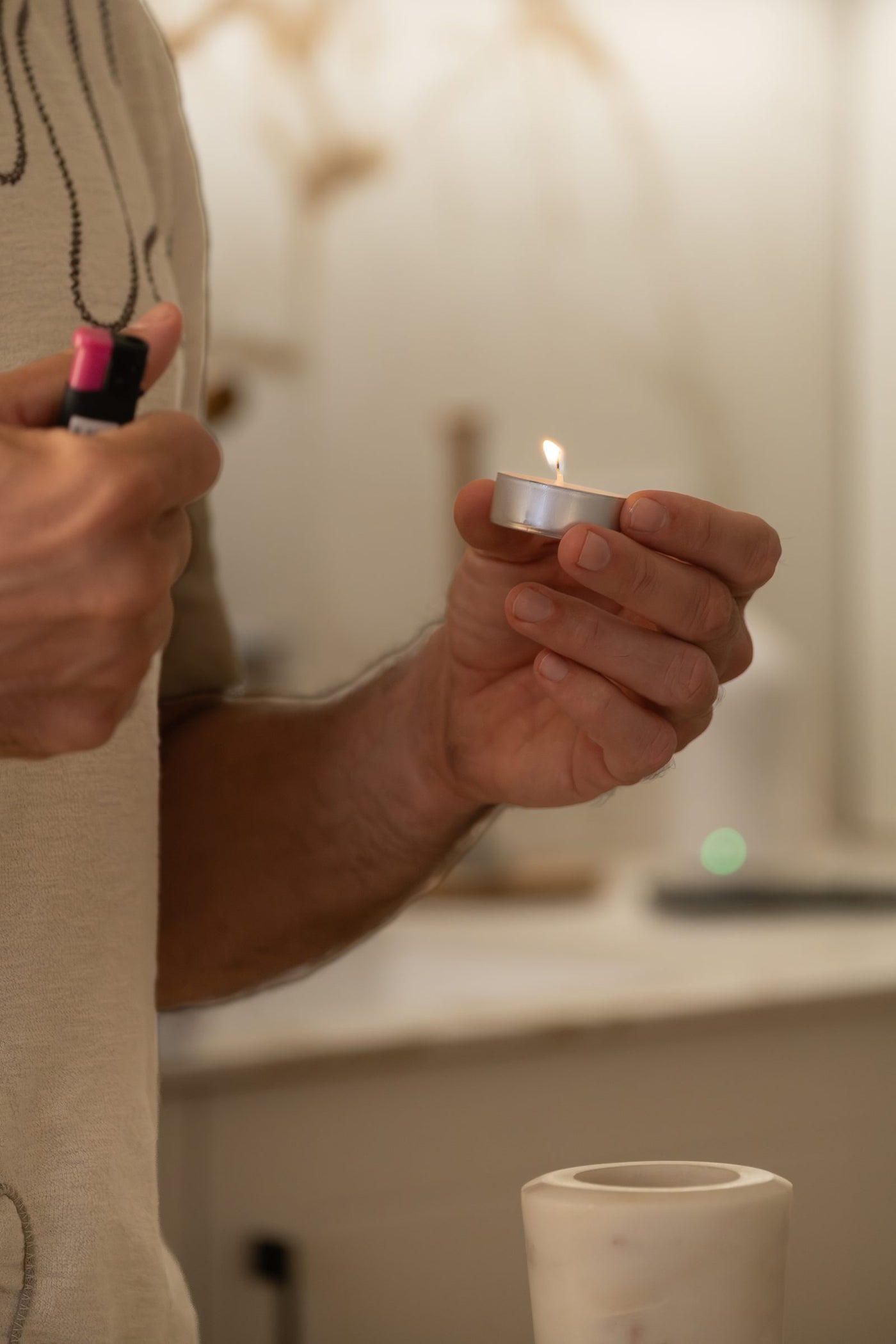 A hand lighting a tea light above the open marble diffuser