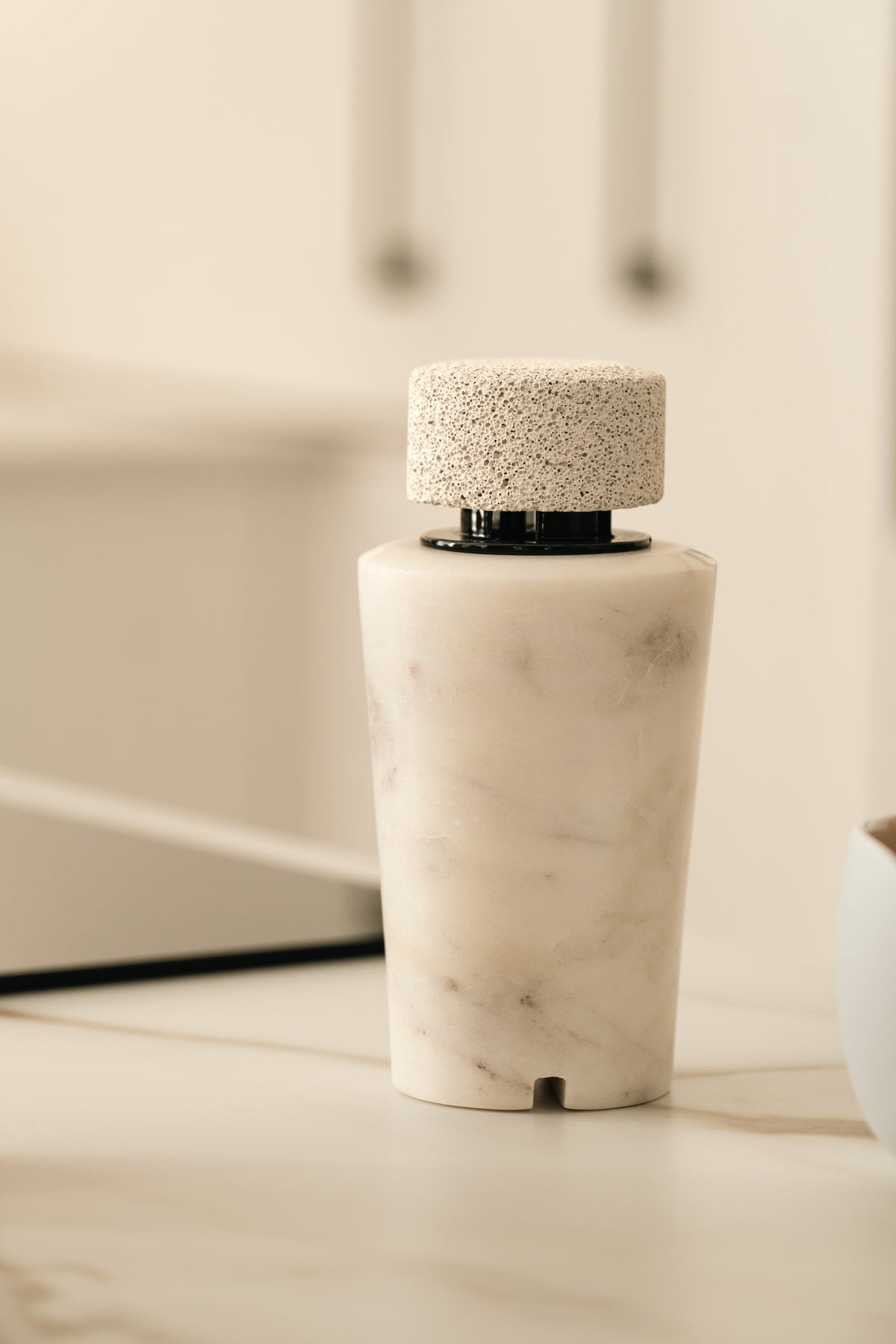 A white marble diffuser with a pumice cap, in soft daylight