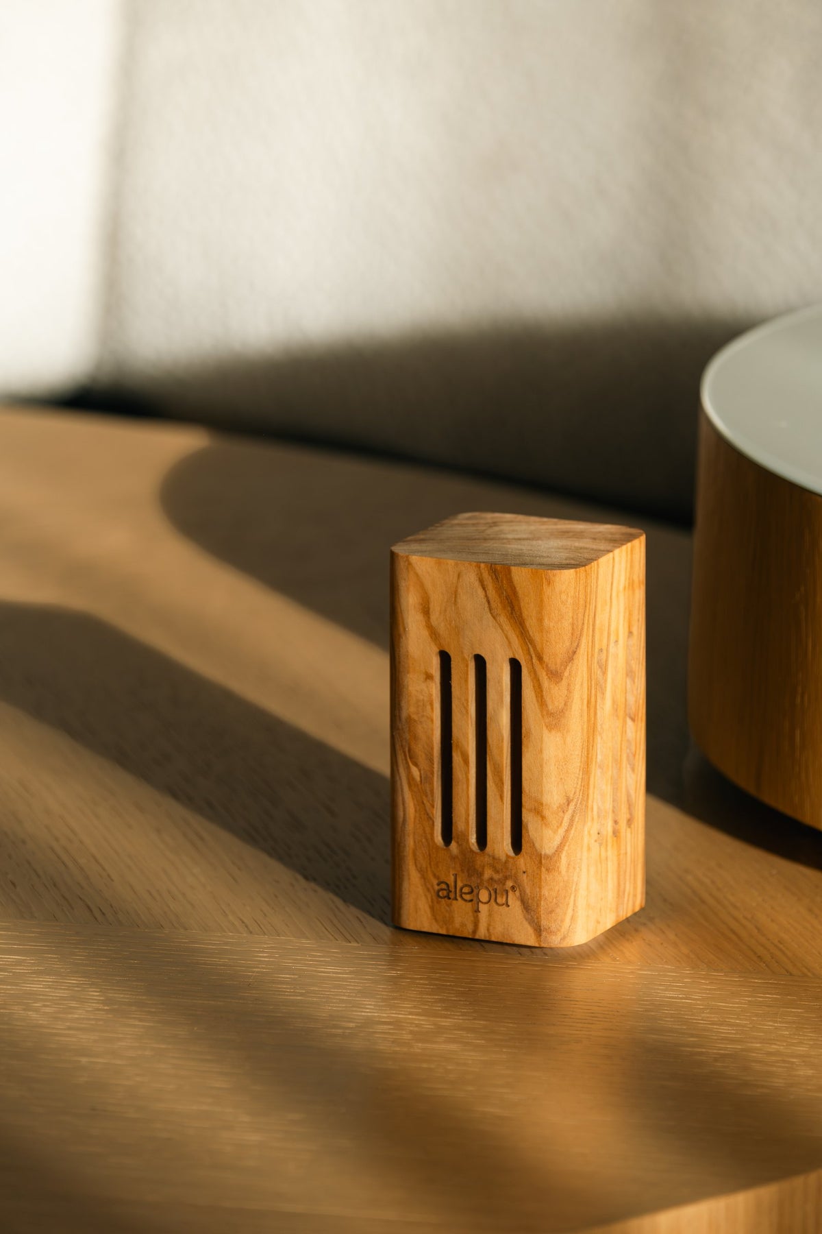The square olive wood diffuser in low sun on a wooden table