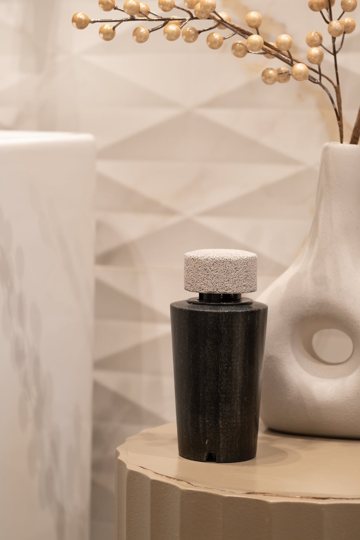 The dark marble diffuser beside a sculptural white vase