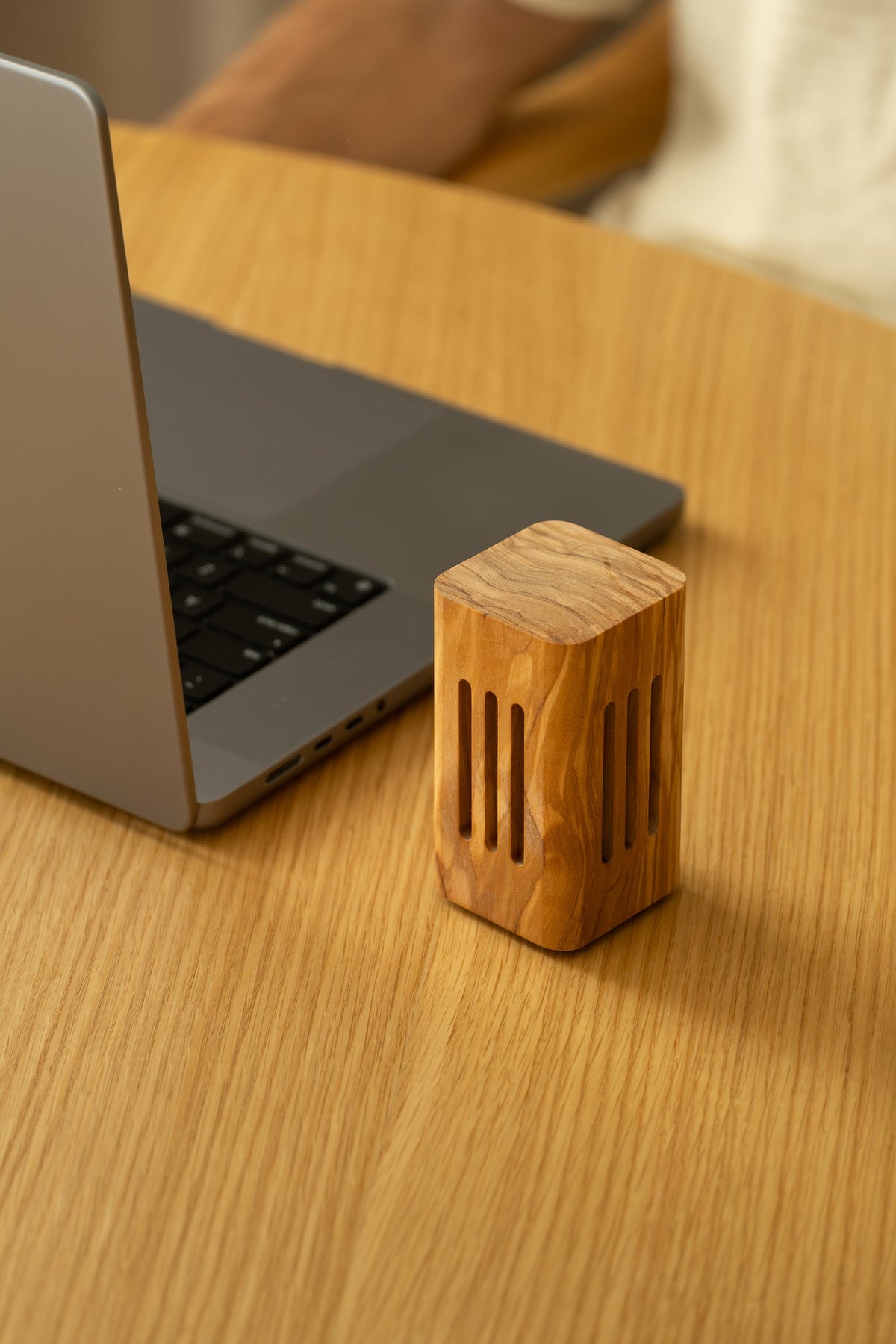 The square olive wood diffuser beside a laptop