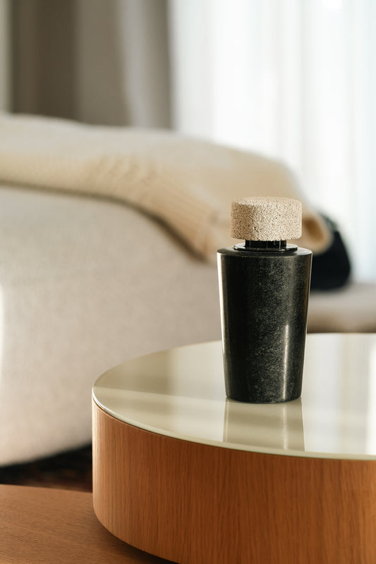 The dark marble diffuser on a glass-topped side table