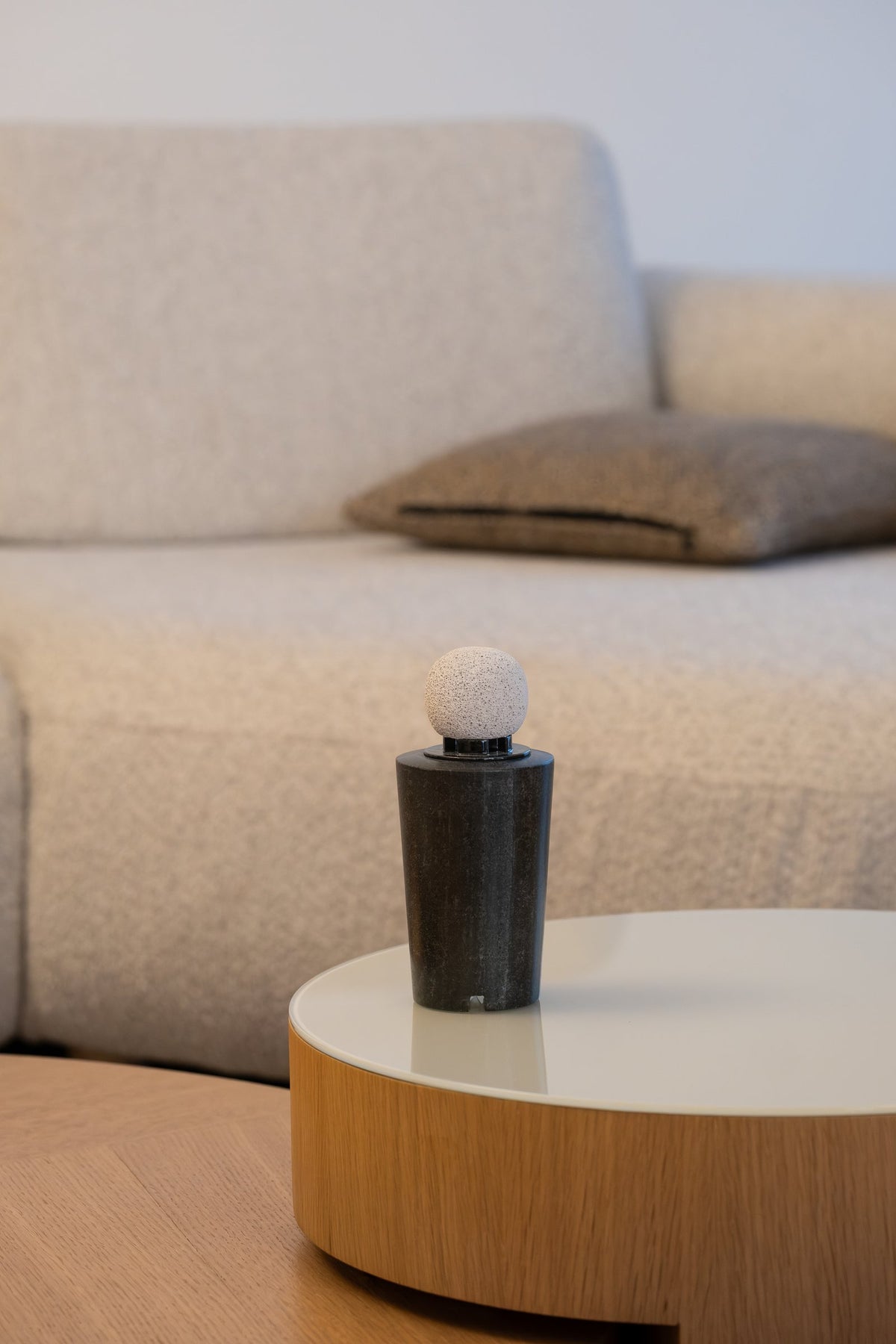 The dark marble diffuser with its round pumice stone, a sofa behind