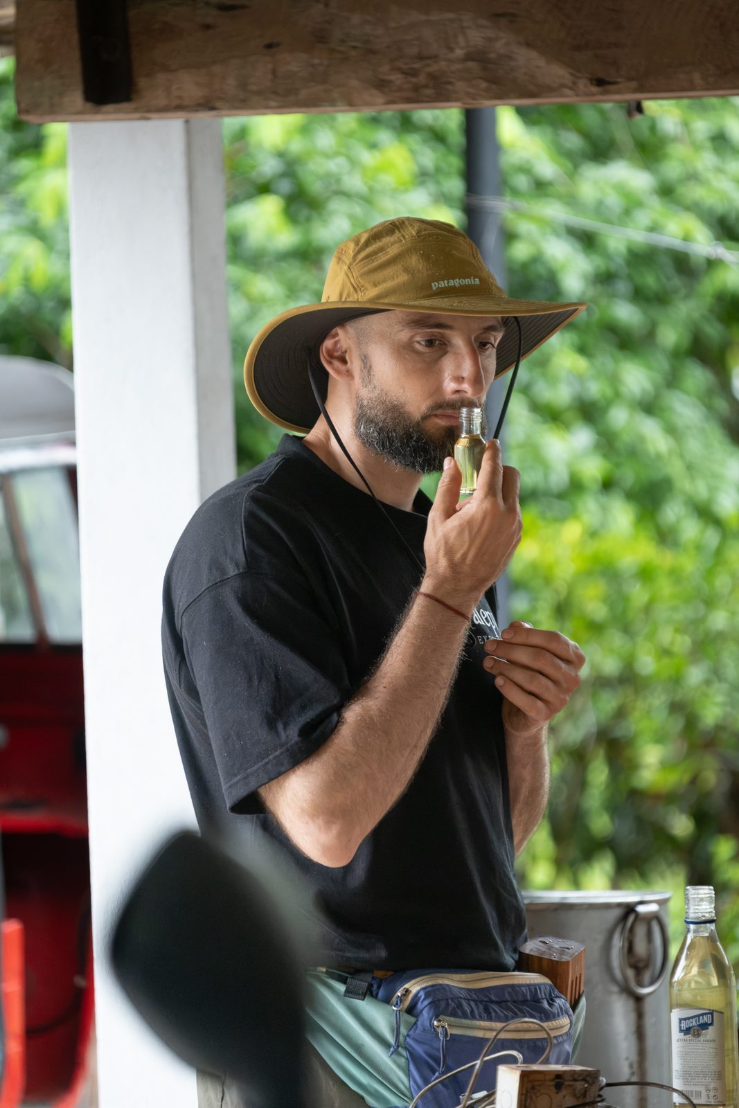 Alepu's founder in a wide-brimmed hat smelling a small bottle of oil
