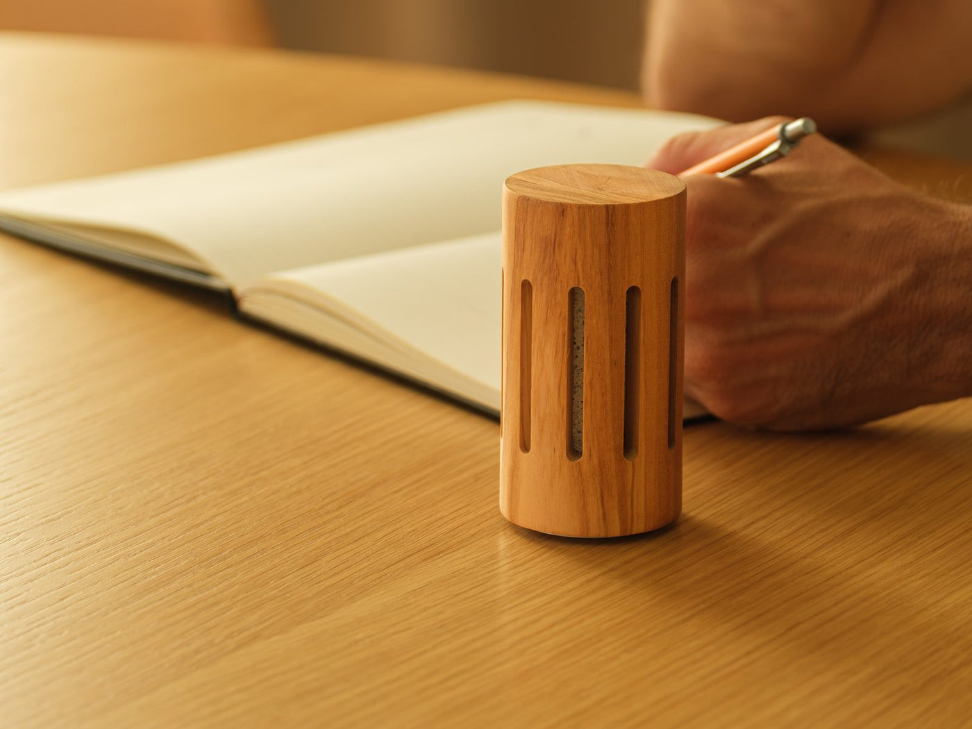 The round olive wood diffuser beside an open notebook in warm light