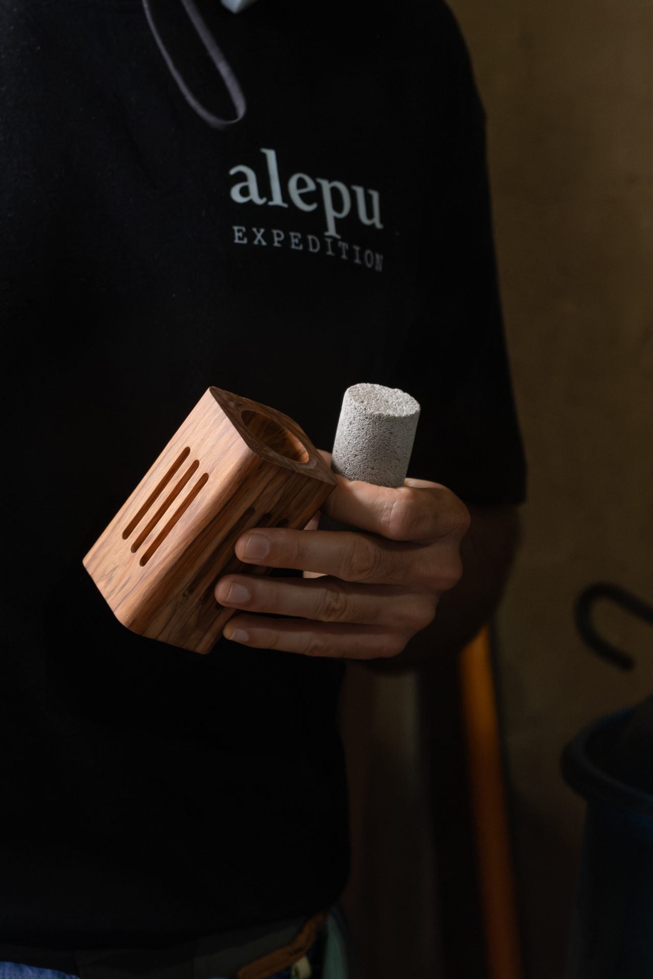 A hand holding the olive wood diffuser with its pumice stone seated in the top