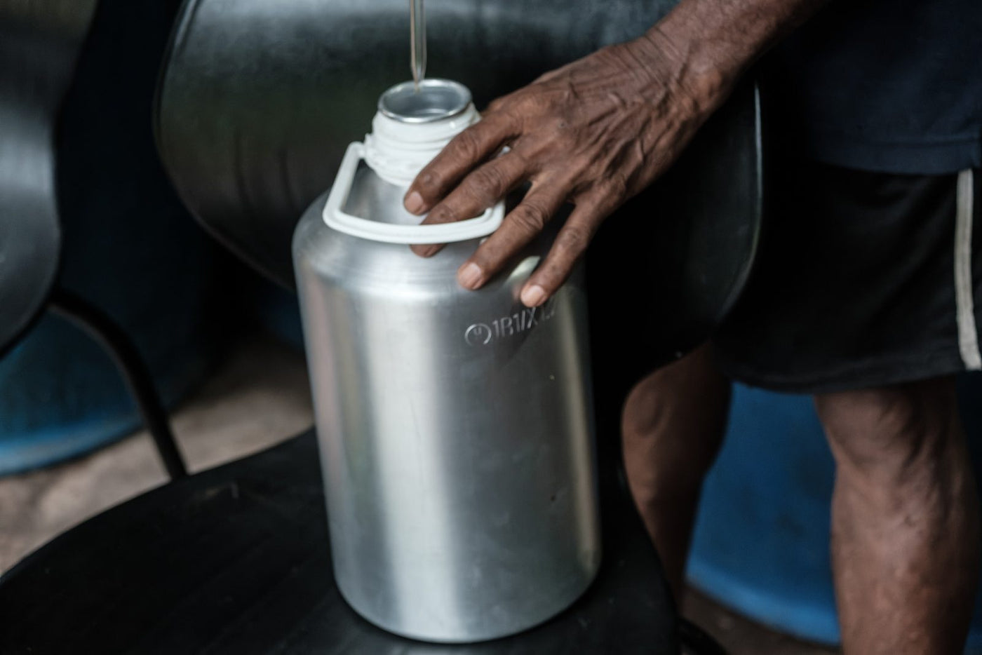 Oil running into a metal canister held steady by hand